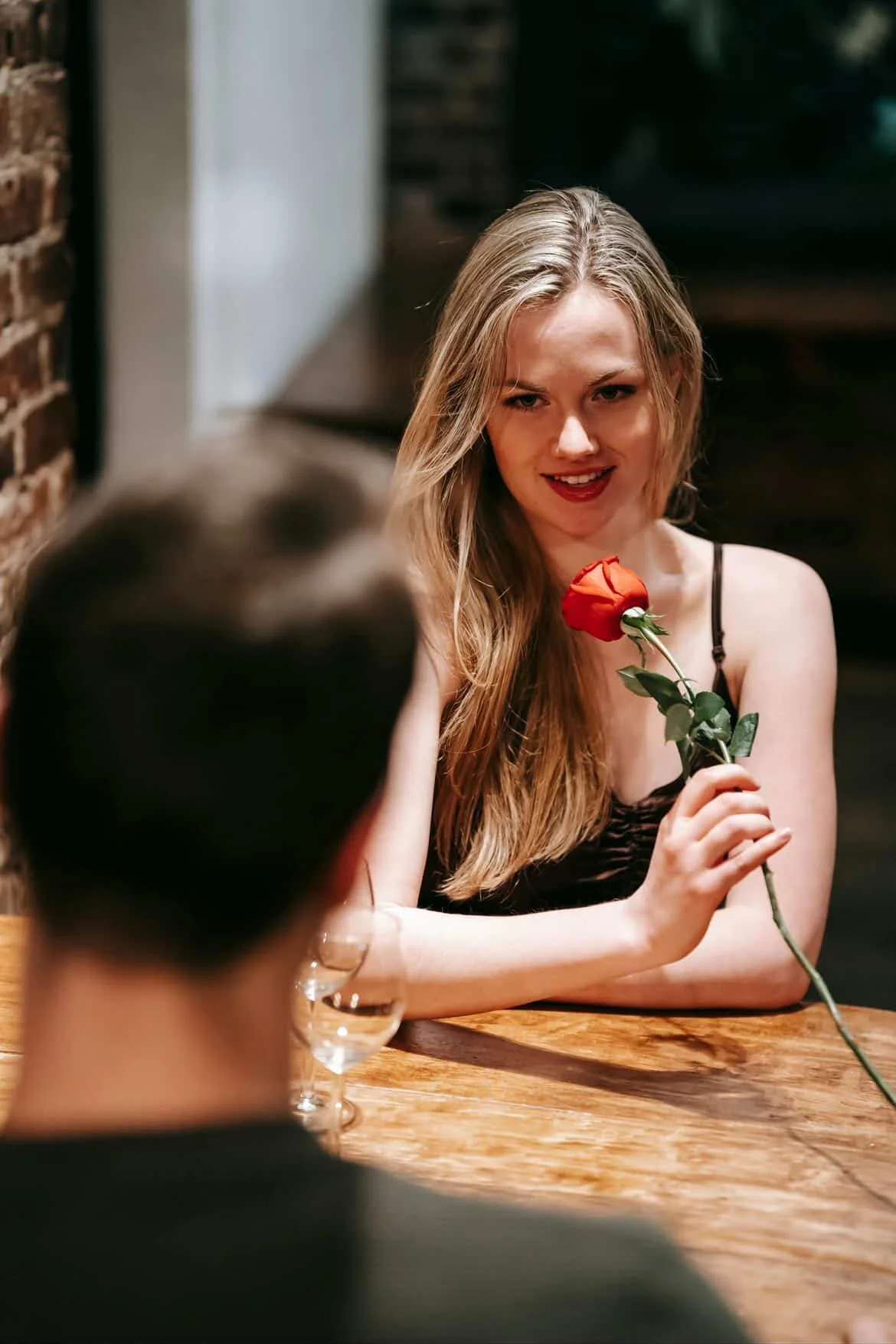 Woman holding a red rose during a romantic dinner meeting in a restaurant